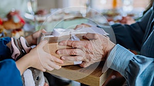 Close-up of grandmother giving gift to her granddaughter during Easter dinner.