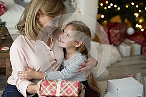 Grandmother giving her little granddaughter a Christmas gift