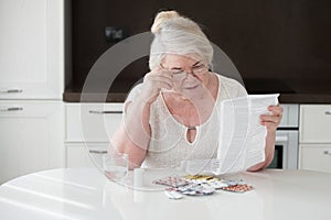 The grandmother in glasses reads the instruction on application of medicines.