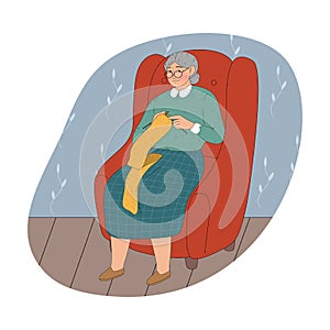 Grandmother in glasses sitting in armchair at home and knitting yellow scarf
