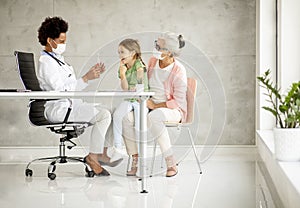 Grandmother with grandaughter at black female doctor