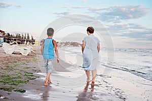 Grandmother with grandchild are resting on sea, running on beach having fun at summer holiday