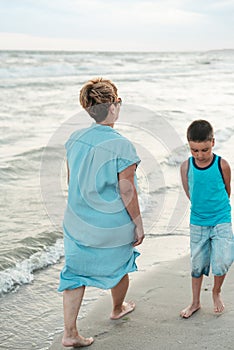 Grandmother with grandchild are resting on sea, running on beach having fun at summer holiday