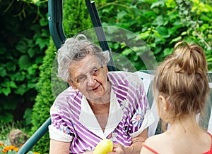 Grandmother with grandchild - senior woman talking at her granddaughter outdoor in nature
