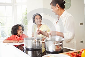 Grandmother And Grandchildren Cooking Meal At Home