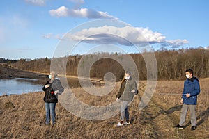 Grandmother and grandchildren in medical masks are walking with a tape measure in their hands observing a safe distance