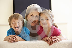 Grandmother And Grandchildren Watching Widescreen TV At Home