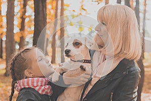 Grandmother with granddaughter in autumn park, girl hugging grandmother and her jack russell terrier dog. Generations