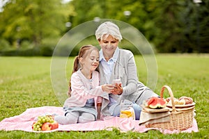 Grandmother and granddaughter with cell at park