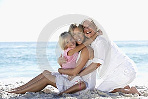 Grandmother With Granddaughter And Daughter Relaxing On Beach