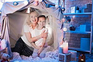 Grandmother and granddaughter are embracing each other in blanket house at night at home.