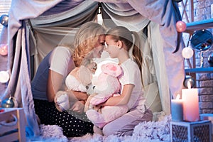 Grandmother and granddaughter with fluffy rabbits in blanket house at night at home.