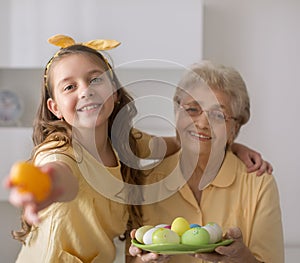 Grandmother with granddaughter are holding Easter eggs