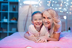 Grandmother and granddaughter are hugging at night at home.
