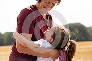 Grandmother and granddaughter hugging in wheat field. Concept of happy family