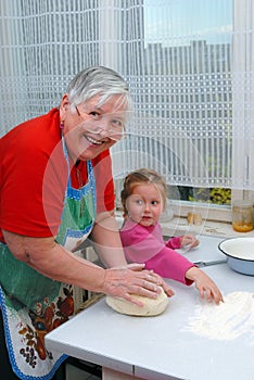 Grandmother and granddaughter knead the dough