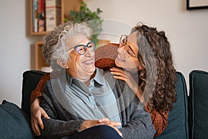 Grandmother and granddaughter laughing and embracing at home