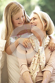 Grandmother With Granddaughter Laughing Together On Sofa