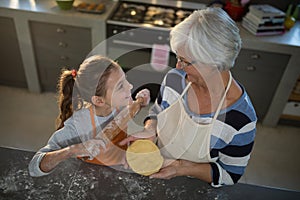 Grandmother and granddaughter looking at each other while holding dough and rolling pin
