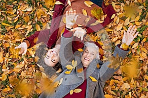 Grandmother and granddaughter lying on foliage and enjoy the autumn