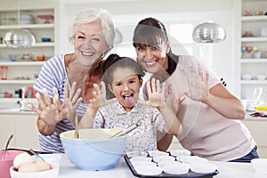 Grandmother, Granddaughter And Mother Baking Cake In Kitchen