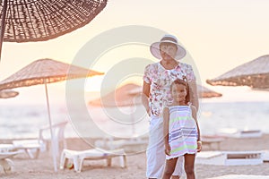 Grandmother and granddaughter posing on the beach at the sunset time. Concept of friendly family