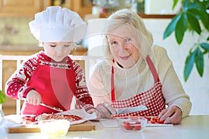 Grandmother and granddaughter preparing pizza