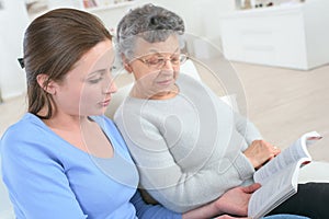 grandmother and granddaughter reading book together at home photo