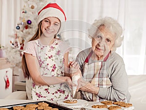 Grandmother with granddaughter decorate cookies