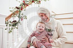 Grandmother With Granddaughter Sits On Stairs At Christmas