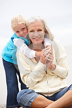 Grandmother And Granddaughter Sitting On Beach