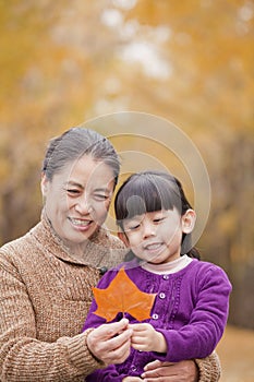 Grandmother and granddaughter smiling and looking at leaf together