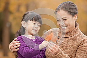 Grandmother and granddaughter smiling and looking at leaf together