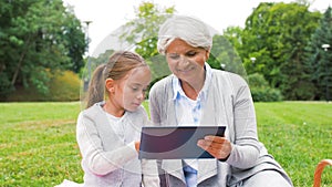 Grandmother and granddaughter with tablet at park