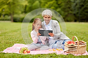 Grandmother and granddaughter with tablet at park