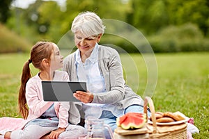 Grandmother and granddaughter with tablet at park