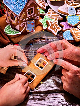 Grandmother and granddaughter together make a gingerbread house for Christmas.