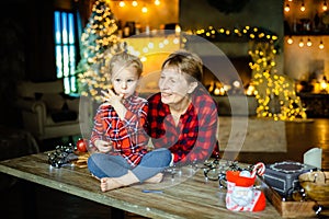 Grandmother and granddaughter together meet Christmas morning in a hunting house decorated with garlands.