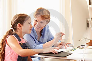 Grandmother And Granddaughter Using Computer At Home