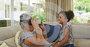 Grandmother and granddaughter using virtual reality headset at home