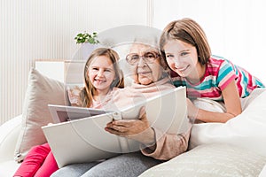 Grandmother with granddaughters looking family photo album