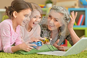 Grandmother and granddaughters playing on laptop