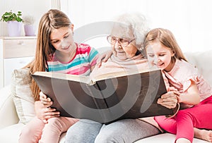 Grandmother with granddaughters reading book