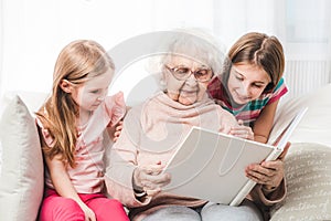 Grandmother with granddaughters reading book