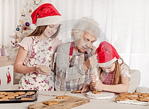 Grandmother with granddaughters soak cream decorating cookies with cream