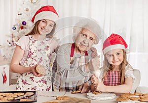 Grandmother with granddaughters soak cream decorating cookies with cream