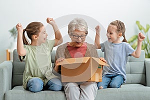 Grandmother and granddaughters are unpacking cardboard box