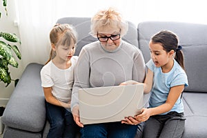 Grandmother with granddaughters use a computer