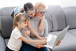 Grandmother with granddaughters use a computer