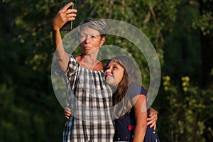 Grandmother with granddaugther making selfi outdoor at evening photo